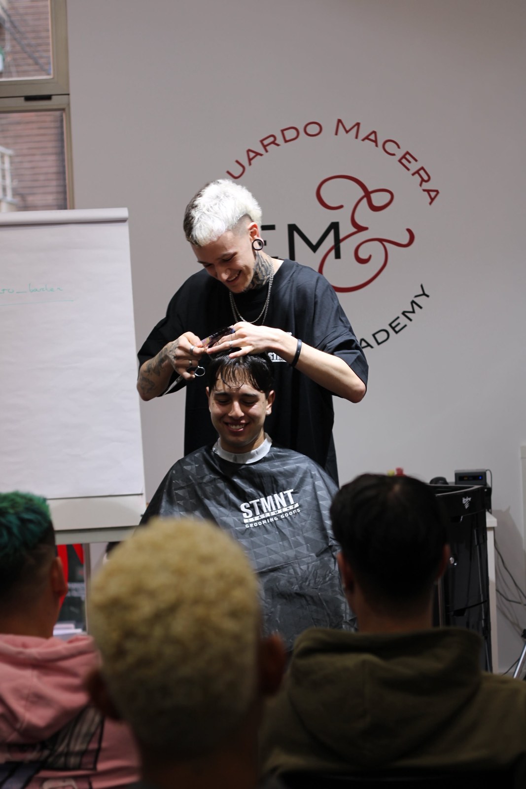 Alberto realizando una demostración de corte ante alumnos en una academia